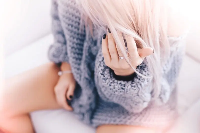 Femme assise jambes nues en pull, illustrant la gêne intime causée par une mycose vaginale